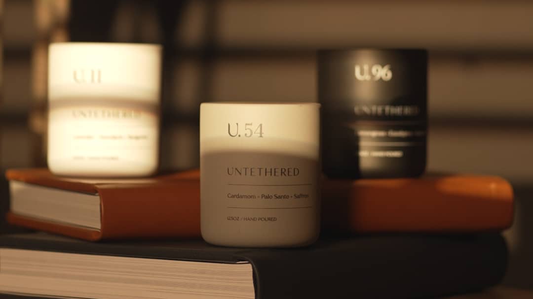 Lit Untethered U.54 luxury candle with double flame, featuring cardamom, palo santo, and saffron notes, creating a warm and elegant home fragrance ambiance - Untethered Official Home Fragrance Blog